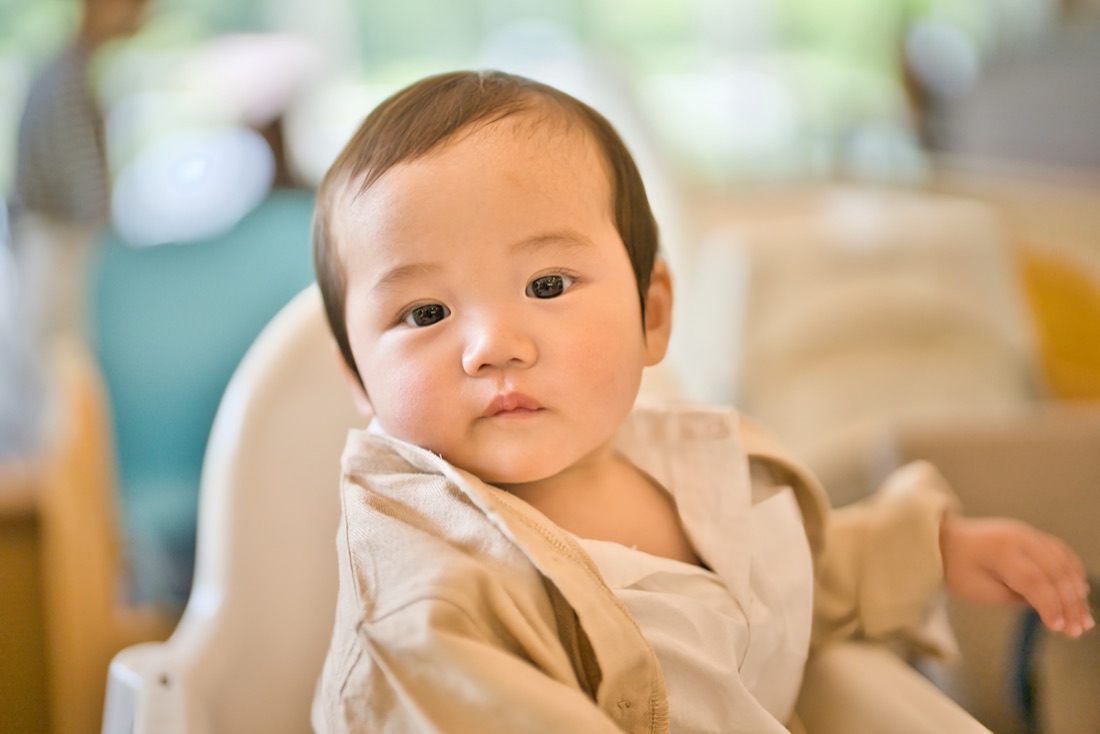 ハイチェアに座ってこちらを見つめる赤ちゃんのポートレート